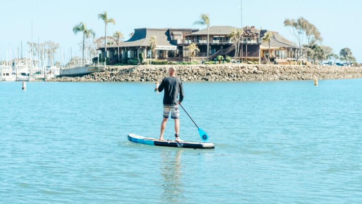 Coastal living - guy on a board paddle